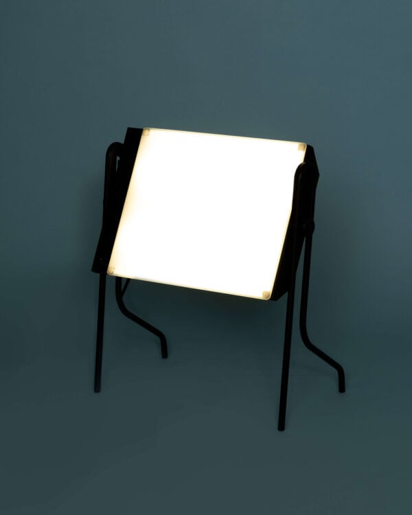 BOXelite desk lamp side view lit on a turquoise background