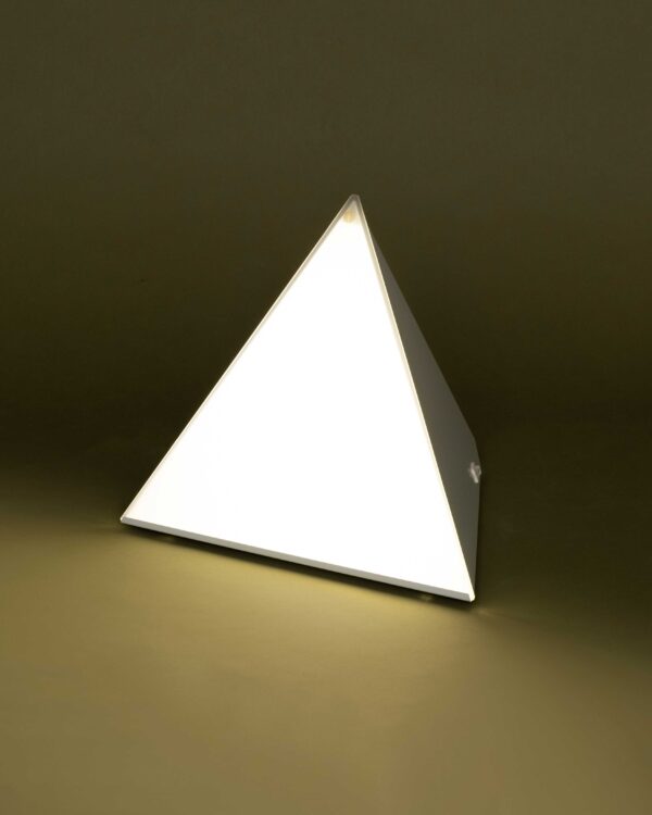 LUXOR desk lamp glowing with 10,000 Lux light therapy on an olive background
