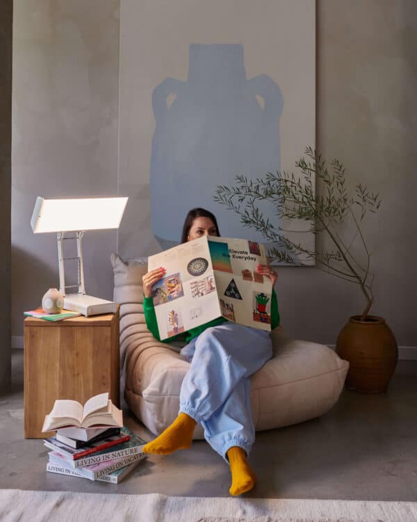 NLT Desk Lamp II beside a woman reading the paper on a chair